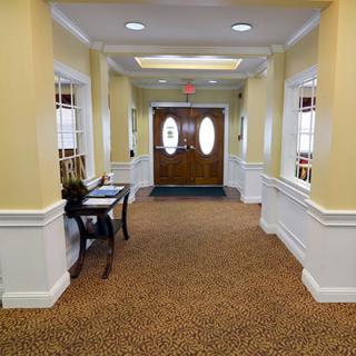 A well-lit hallway with a carpeted floor leading to double doors.