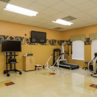 A small gym with fitness equipment including treadmills and televisions.