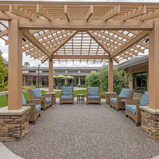 A stylish outdoor patio featuring a pergola and comfortable seating surrounded by lush landscaping.