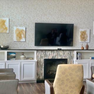 A modern living room with a mounted TV above the fireplace, surrounded by stylish artwork and comfortable seating.