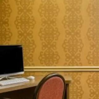 A workspace with a computer on a desk and an empty chair against patterned wallpaper.