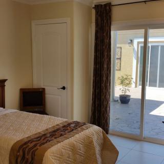 A cozy bedroom with a bed, sliding glass door, and sunlight streaming in.