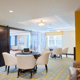 A modern dining area with elegant chairs and tables, featuring neutral colors and contemporary lighting.