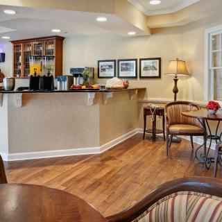 A cozy cafe interior with a bar counter and seating area, featuring wood flooring and warm lighting.