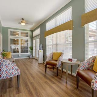 A cozy living room with ample natural light, featuring stylish chairs and a hardwood floor.