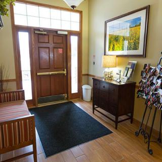 A cozy entrance with a wooden door, mat, and seating area.