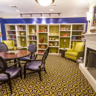 A cozy library room with bookshelves, a fireplace, and comfortable seating.