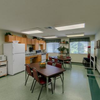 A communal kitchen and dining area with tables, chairs, and appliances.