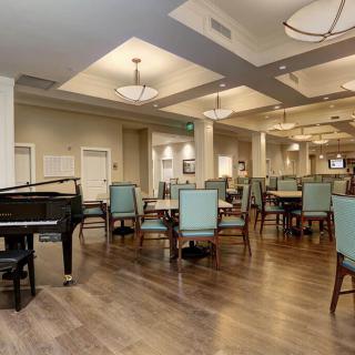 A spacious dining area with a grand piano, featuring elegant lighting and modern furnishings.