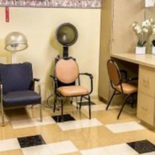 An interior view of a hair salon featuring chairs, dryer equipment, and a mirror with counter space.