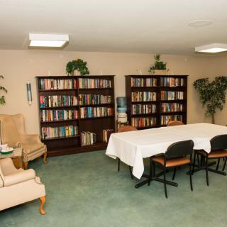 A small library or meeting room with bookshelves, a table, and chairs.
