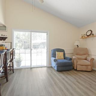 A cozy living room with two armchairs, wood flooring, and a sliding glass door letting in natural light.