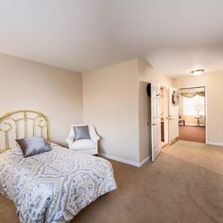 A cozy bedroom with a single bed, chair, and neutral decor.