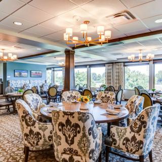 A beautifully decorated dining room featuring elegant chairs, chandeliers, and large windows with scenic views.