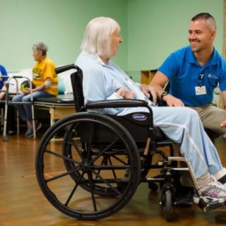 A healthcare worker interacting with an elderly person in a wheelchair.