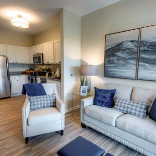 A modern and cozy open-concept living room and kitchen with elegant furnishings and blue accent decor.