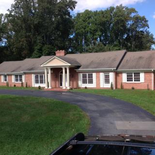 A brick ranch-style house with a large lawn and curved driveway.