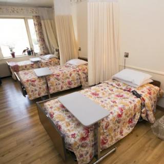A hospital room featuring two beds with floral bedding and curtain dividers.