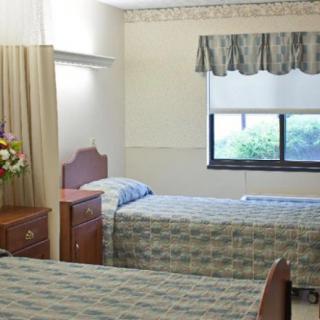 A hospital room with two beds and a window.