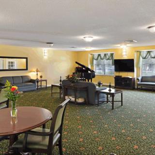 A spacious living room featuring a grand piano, ample seating, and a television.