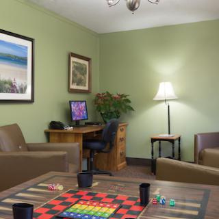A cozy lounge area featuring comfortable seating, a computer workstation, and a board game ready for play.
