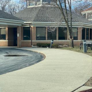 A view of a building with a curved sidewalk and trees in the surroundings.
