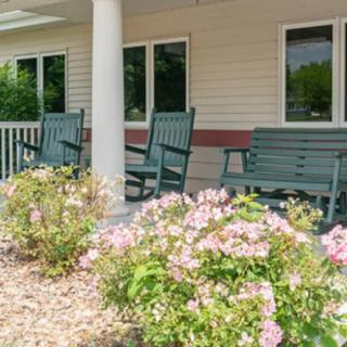 A charming porch with green rocking chairs and blooming flowers.