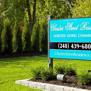 Sign for an assisted living community surrounded by greenery.