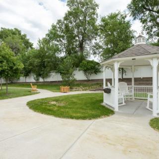 A serene outdoor setting featuring a white gazebo along a winding pathway surrounded by lush greenery.