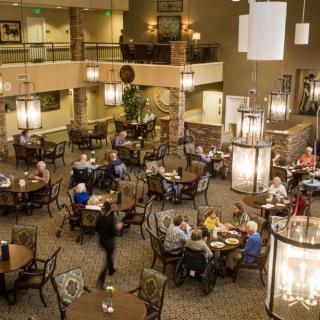 A lively dining area with people gathered at tables, enjoying a meal in a warmly lit setting.