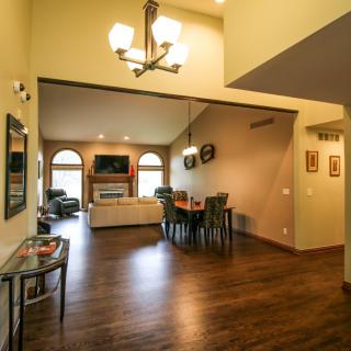Spacious living and dining area with vaulted ceilings, elegant chandelier, and wood flooring.