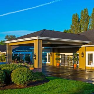 A beautifully lit building entrance surrounded by lush greenery under a clear blue sky.