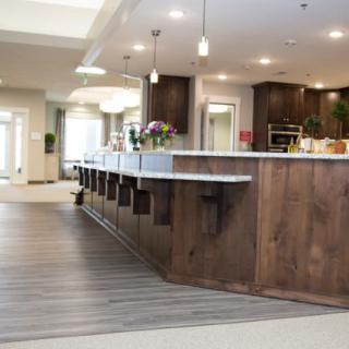 A modern kitchen interior featuring a wooden bar counter and stylish lighting.
