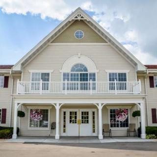 A symmetrical building with a prominent entrance and balcony, set against a cloudy sky.