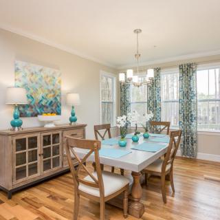 A bright and inviting dining room with a wooden table, elegant chairs, and tasteful decor.
