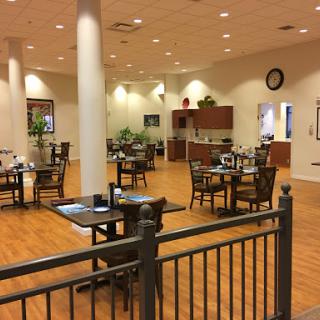 A spacious dining area featuring tables, chairs, and a kitchen in the background.