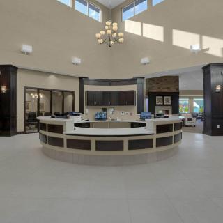 A modern lobby with a curved reception desk and large chandelier.