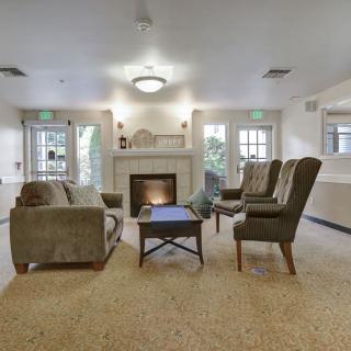 A cozy living room with a fireplace, sofa, armchairs, and a coffee table.