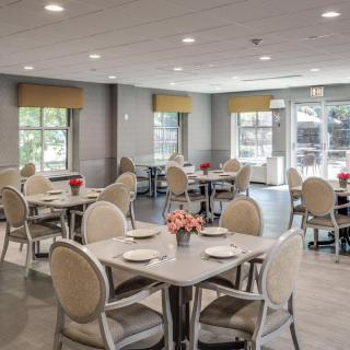 A neatly arranged dining area with elegant tables and chairs, featuring large windows allowing natural light to fill the space.