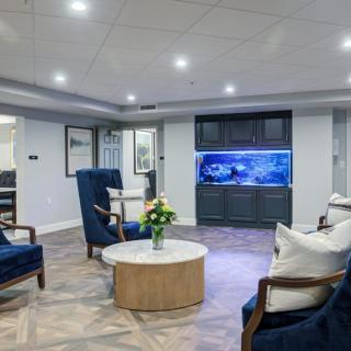 A modern living room with elegant seating, featuring a large aquarium and stylish decor.