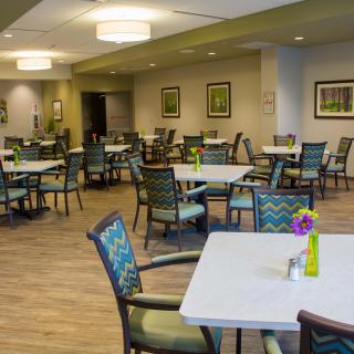 A modern dining room with empty tables and chairs, featuring contemporary decor.