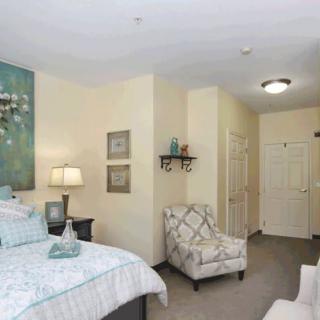 A cozy bedroom with a bed, armchair, and decorative artwork on the walls.