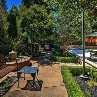 A serene garden patio with lush greenery and outdoor seating.