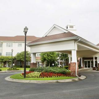 The image shows the entrance to a building with landscaped surroundings.