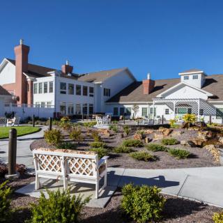 A sunny day at a well-maintained building with a landscaped garden and benches.