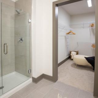 A modern bathroom with a glass shower and adjoining dressing area.