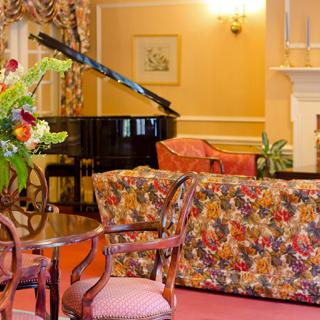 Elegant living room with a grand piano and floral-patterned furniture.