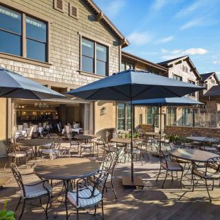 An inviting outdoor patio area with tables, chairs, and umbrellas under a clear blue sky.