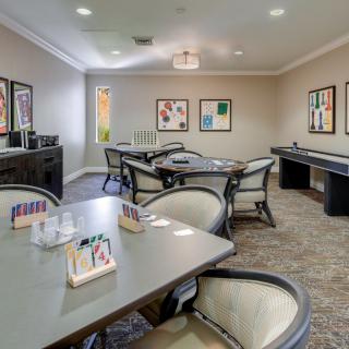 A cozy game room featuring multiple tables, chairs, and wall artwork.