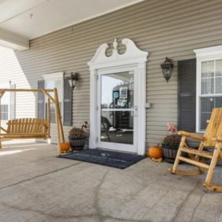A cozy porch with a wooden swing, rocking chair, and seasonal decorations.